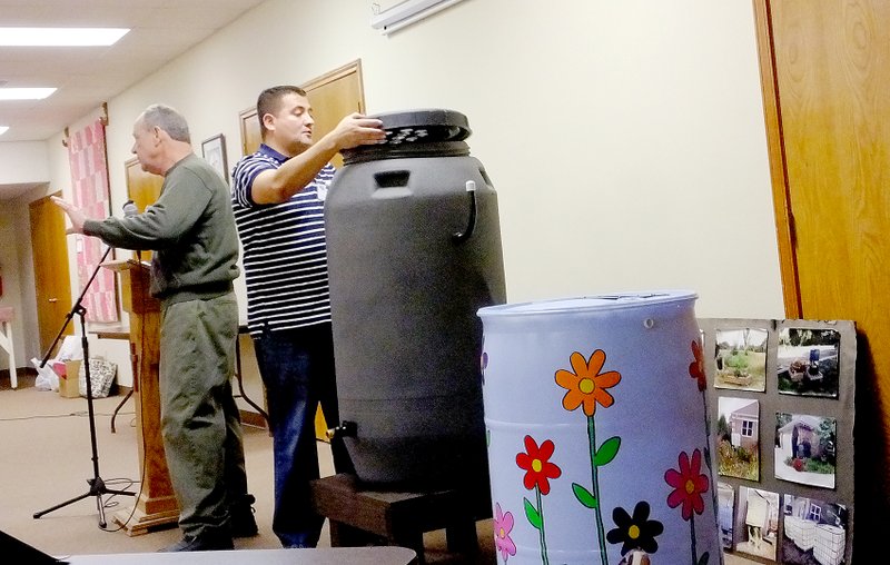 Lynn Atkins/The Weekly Vista Rick Gilbert and Luis Gonzalez show the Bella Vista Garden Club a rain barrel that will collect rain from roofs for outside use. They provided the program at the February meeting.