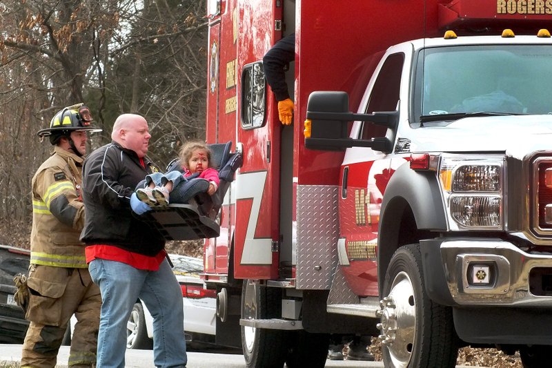 TIMES photograph by Annette Beard Alanny Oaks, 4, was carried to the ambulance in her car seat by Josh &#8220;Moose&#8221; Dunavan, off-duty firefighter/emergency medical technician and Little Flock fire chief. Caring for Alanny in the ambulance were Firefighter/EMT Brandon Beyer and Firefighter/Paramedic Michael Anderson. Alanny was a passenger in a truck involved in a head-on collision Tuesday, Feb. 24, on Ark. Hwy. 94.