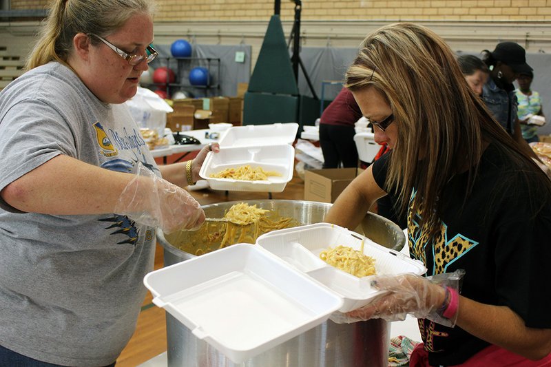 Kristi Rogers, left, and Shelia Williams, along with other members of the Sigma Epsilon Chapter of Phi Beta Lambda at South Arkansas Community College, prepare plates of chicken spaghetti, green beans, rolls, desserts and bottled water. The fundraising event was held Wednesday at the SouthArk gymnasium to help defray expenses for PBL members’ participation in the Arkansas PBL Leadership Conference.
