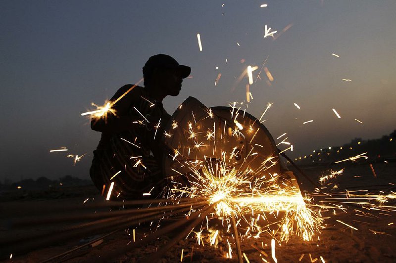 A worker cuts iron rods last month at a construction site in Ahmadabad, India. Economists say the world economy is in less peril than a year ago because of cheap oil and lower interest rates. 