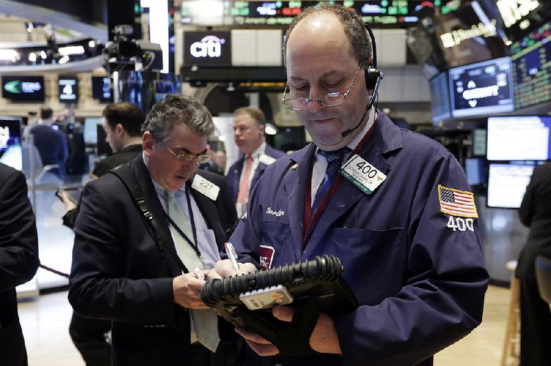 Trader Gordon Charlop (front) works Wednesday on the floor of the New York Stock Exchange as stocks fell a second day, dropping below record highs set earlier this week. 