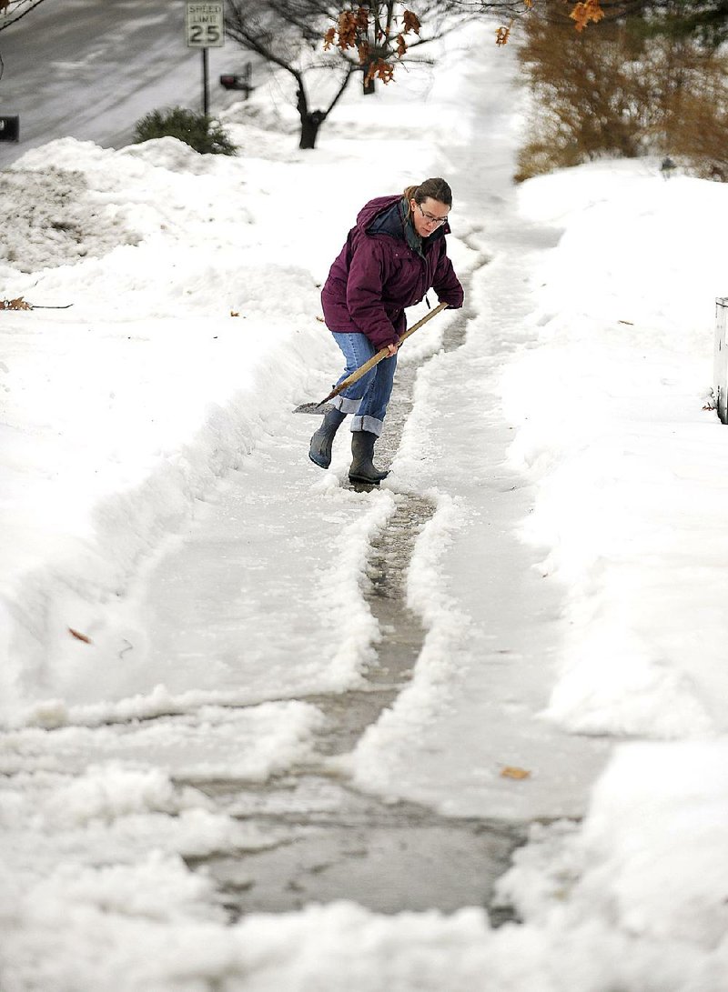 Janice Wilson scrapes ice off her sidewalk Wednesday in State College, Pa. 