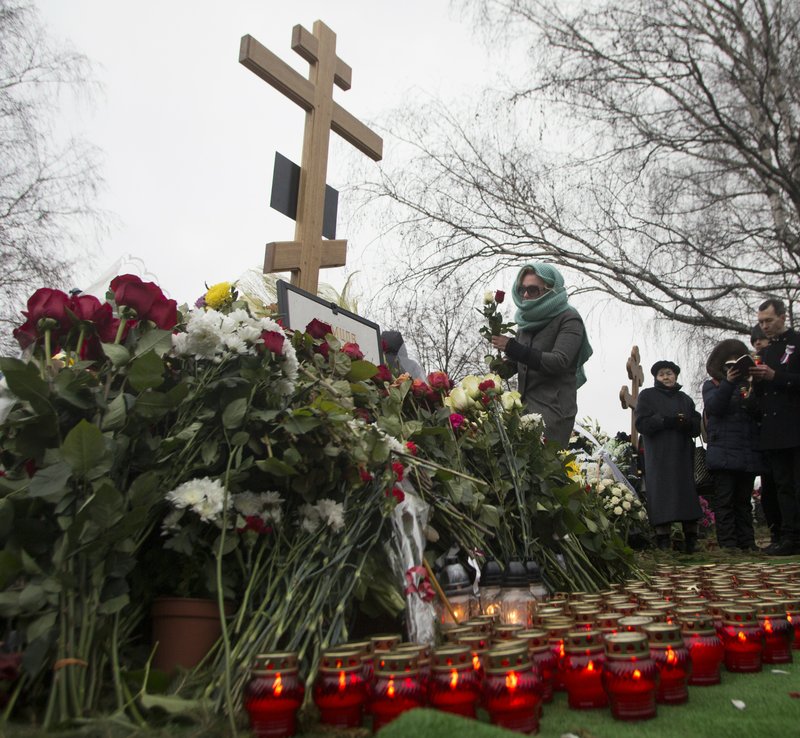 A woman lays flowers at the grave of Boris Nemtsov after a burial ceremony at Troekurovskoye cemetery in Moscow, Russia, Tuesday, March 3, 2015.  One by one, thousands of mourners and dignitaries filed past the white-lined coffin of slain Kremlin critic Boris Nemtsov on Tuesday, many offering flowers as they paid their last respects to one of the most prominent figures of Russia's beleaguered opposition.