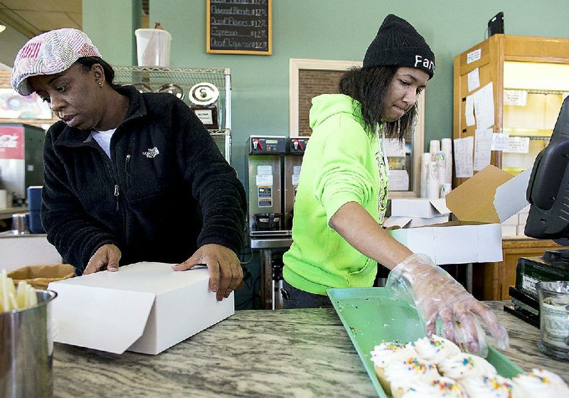 April Hemphill (left) and Kamronn Keels box up baked goods for a customer Thursday at Community Bakery on Main Street in Little Rock. Owner Joe Fox said he makes it a point to stay open in bad weather and planned to stay open until 3 p.m.