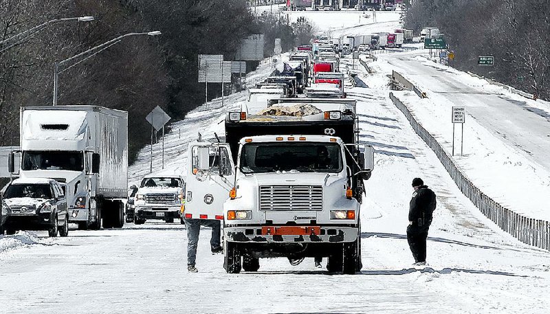 An Arkansas Highway and Transportation Department truck spreads salt on a stretch of eastbound Interstate 30 at Benton’s Sevier Street exit Thursday morning as traffic backs up. 