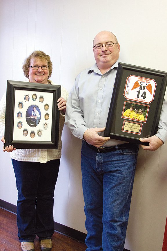 Linda and Stan Valley hold photos of their late son, Brian, and a plaque from the memorial run they have 
established in his name. The Brian Valley Memorial 5K+1 will be run April 25 in Jacksonville.
