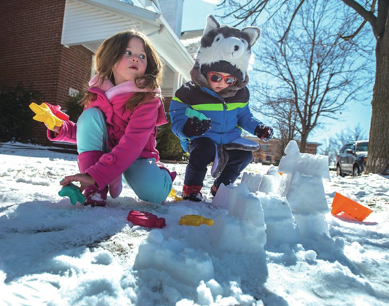 Maddie Gladden, 5, (left) and Tristin Gladden 4, play in the snow Thursday outside their Springdale home. The children were enjoying the slightly warmer temperature by building snowmen, a snow wall and snow balls. For photo galleries, go to nwadg.com/photos.