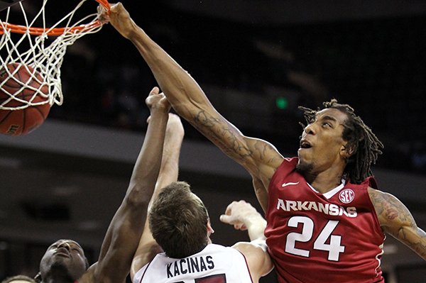 Arkansas' Michael Qualls (24) dunks over South Carolina's Mindaugas Kacinas (25) during the second half of an NCAA college basketball game, Thursday, March 5, 2015, in Columbia, S.C. At left is Arkansas' Alandise Harris. Arkansas won 78-74. (AP Photo/Travis Bell)