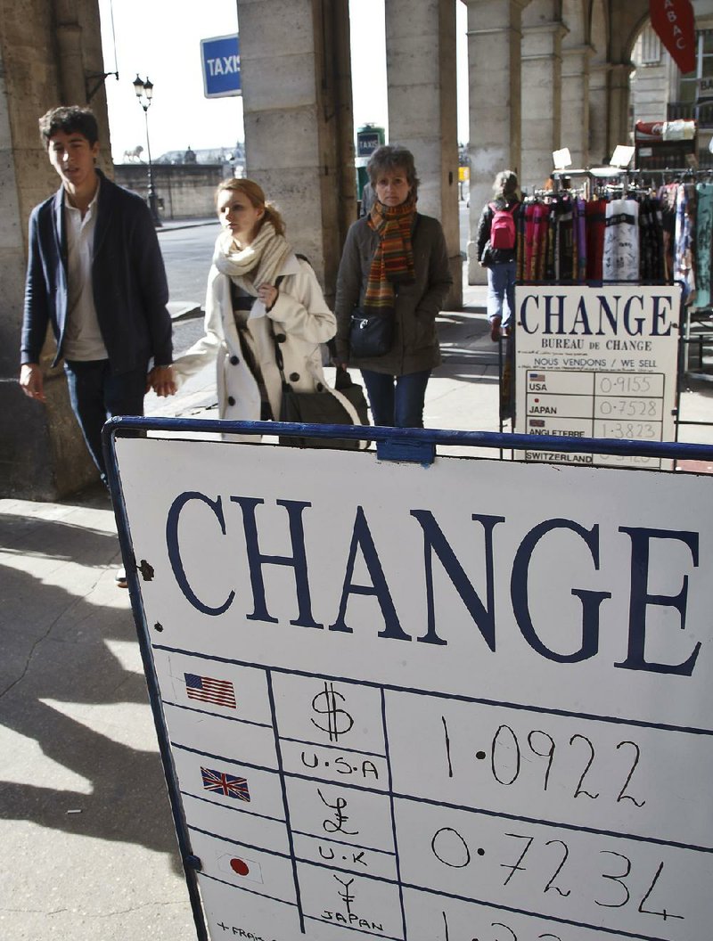 People walk past exchange rate boards in Paris, Friday, March 6, 2015. The euro could soon be doing something it's only done a couple of times in its 16-year existence, trading 1-to-1 with the dollar. Europe's single currency has since May been on a downward trajectory again the dollar, mainly because of the divergence in economic performance between the eurozone an the United States. (AP Photo/Michel Euler)