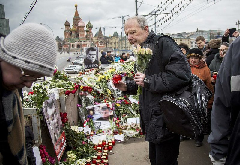 Mourners following the Russian tradition of memorializing a person nine days after a death lay flowers and votive candles at the place where Boris Nemtsov, a charismatic Russian opposition leader and sharp critic of President Vladimir Putin, was gunned down on Friday, Feb. 27, 2015 near the Kremlin, in Moscow, on Saturday, March 7, 2015.  Two suspects have been detained in the killing a week ago of opposition politician Boris Nemtsov, the head of Russia's federal security service said Saturday, an announcement received with both skepticism and reserved satisfaction by some of Nemtsov's comrades. (AP Photo/Alexander Zemlianichenko)