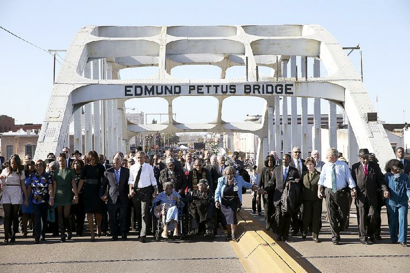 President Barack Obama leads a march across the Edmund Pettus bridge, 50 years to the day after “Bloody Sunday” in Selma, Ala., March 7, 2015. In an address, Obama rejected the notion that race relations have not improved in the years since -- as well as the notion that racism has been defeated. Among the many political figures at the march was former president George W. Bush, at right. (Doug Mills/The New York Times)