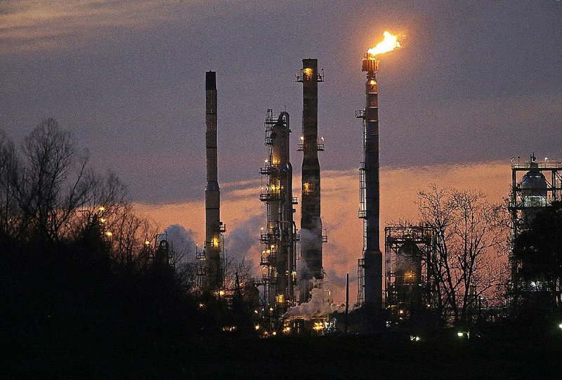 Stacks and burn-off from the Exxon Mobil refinery are seen at dusk in St. Bernard Parish, La., Friday, Feb. 13, 2015. (AP Photo/Gerald Herbert)