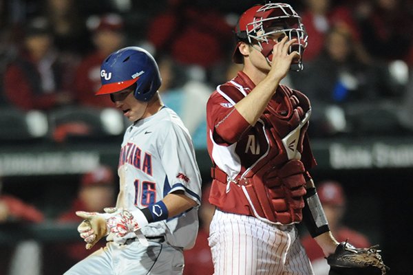 Catcher Tucker Pennell (right) of Arkansas watches as Tyler Frost of Gonzaga scores during the seventh inning Tuesday, March 10, 2015, at Baum Stadium in Fayetteville.