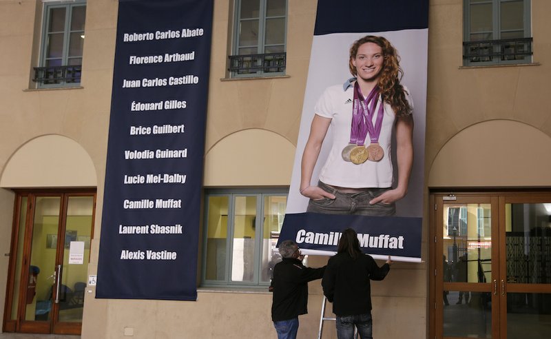 A poster of the recently killed Olympic gold medalist swimmer Camille Muffat is hung Tuesday, March, 10, 2015, at the City Hall of Nice, southeastern France. Argentine recovery teams arrived on March 10 at the site of a helicopter collision to recover the bodies of 10 people, including Muffat, 25, who was participating in a reality TV show. 