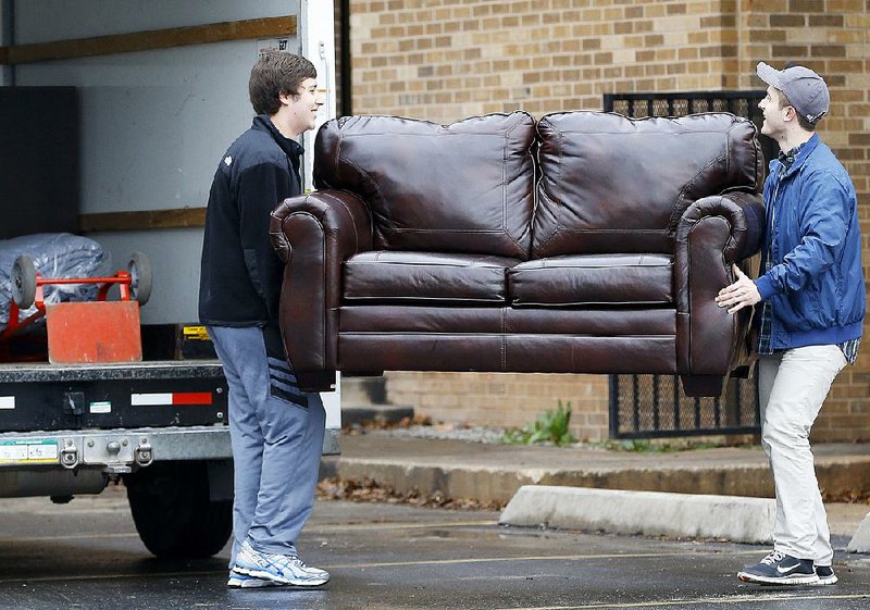 Two men load a couch from the closed University of Oklahoma’s Sigma Alpha Epsilon fraternity house into a truck Tuesday in Norman, Okla. The fallout continued to reverberate Tuesday over a racially biased chant captured on video during a fraternity event.