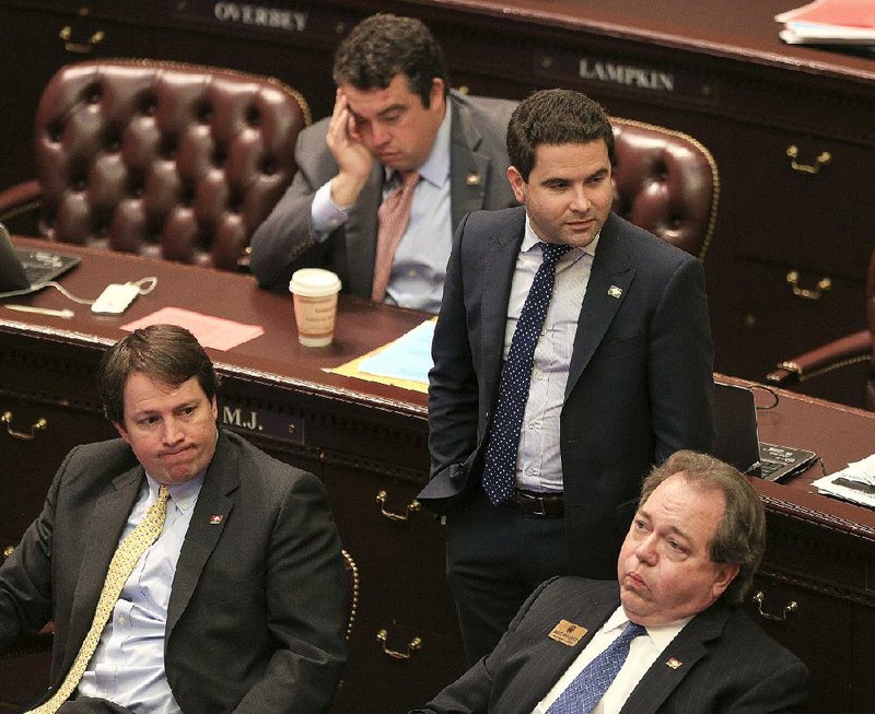 Democratic state Reps. (from left) Clarke Tucker of Little Rock, Michael Gray (rear) of Augusta, Warwick Sabin of Little Rock and David Whitaker of Fayetteville listen to announcements Tuesday while waiting for the House to adjourn for the day. 