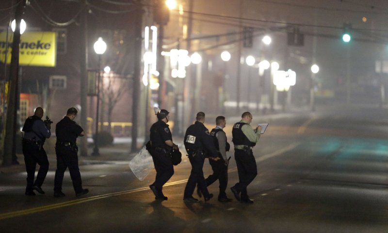 Police canvass the area as they investigate the scene where two police officers were shot outside the Ferguson Police Department Thursday, March 12, 2015, in Ferguson, Mo.