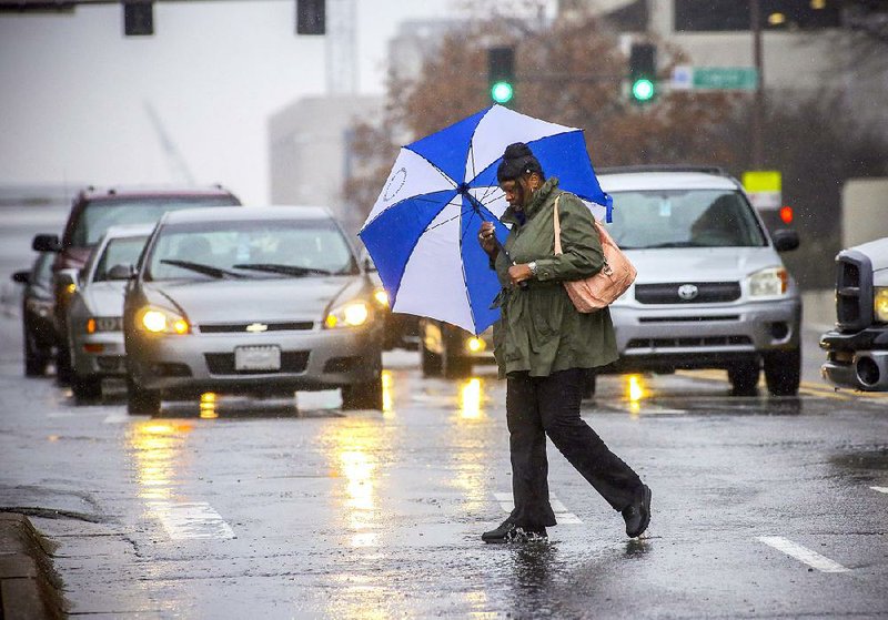 Cassandra Hussey crosses a soggy Broadway at Sixth Street on Thursday in Little Rock. The city recorded 3.79 inches of precipitation in the first 11 days of March. 