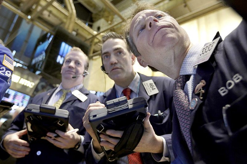 Traders gather Friday at a post on the floor of the New York Stock Exchange, where stocks drifted lower. 