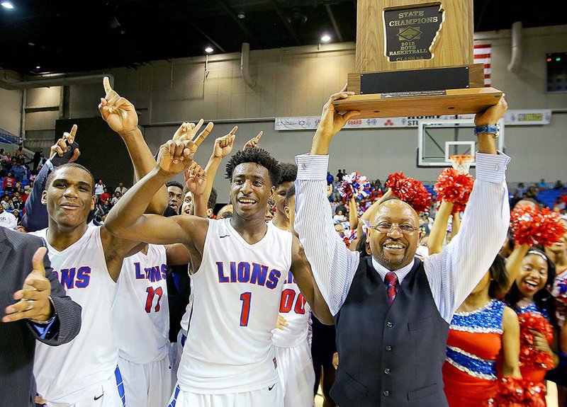 Little Rock McClellan players Karson Hayes (left) and Andre Jones help Coach Chris Threatt show off the Class 5A state championship trophy Saturday after the Crimson Lions defeated Maumelle 82-73 at Bank of the Ozarks Arena in Hot Springs.