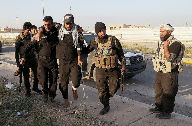 Iraqi Shiite militiamen evacuate a wounded fellow fighter Saturday in Tikrit, where fi erce clashes between Iraqi forces and Islamic State militants were reported as an offensive to retake the city from the rebels continues. 