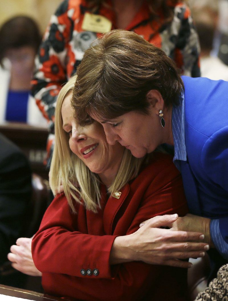 Rep. DeAnn Vaught, R-Horatio, left, is hugged by Rep. Camille Bennett, D-Lonoke, right, in the House chamber at the Arkansas state Capitol in Little Rock, Ark., after Vaught spoke in favor of a bill dealing with reporting of child maltreatment Monday, March 16, 2015. Vaught referred to her own childhood experiences in her speech supporting the bill. (AP Photo/Danny Johnston)