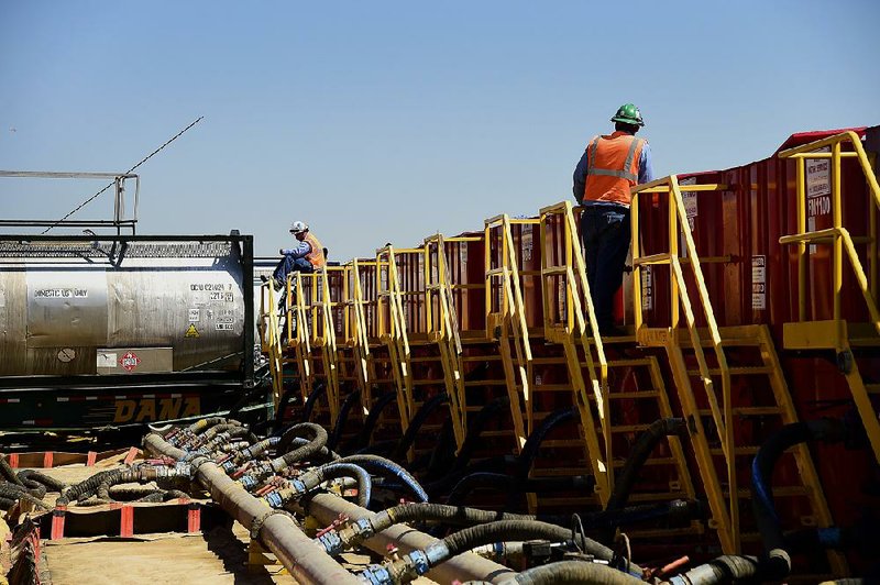 Workers stand next to water tanks in August at an Anadarko Petroleum Corp. hydraulic fracturing site near Dacono, Colo. 