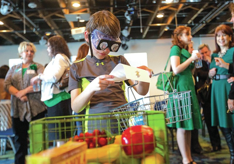 NWA Democrat-Gazette/JASON IVESTER Corbin Gilbert, 8, of Bentonville tries his hand Tuesday at grocery shopping with vision-altering goggles during a news conference for the Scott Family Amazeum at the Wal-Mart Museum in downtown Bentonville. The Amazeum will open July 15. For photo galleries, go to nwadg.com/photos.