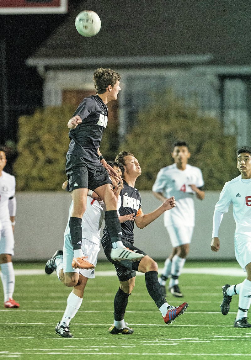 NWA Democrat-Gazette/ANTHONY REYES &#8226; @NWATONYR Wyatt D&#8217;Spain of Bentonville leaps to head the ball Tuesday over Jose Serrano of Springdale High at Bulldog Stadium in Springdale.