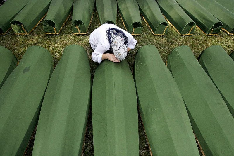 A Bosnian woman weeps near the coffin of a relative at a funeral in 2013 near Srebrenica, the site of the 1995 massacre of 8,000 Muslims. Eight arrests Wednesday by Serbian forces are said to be first of direct participants in the killings. 