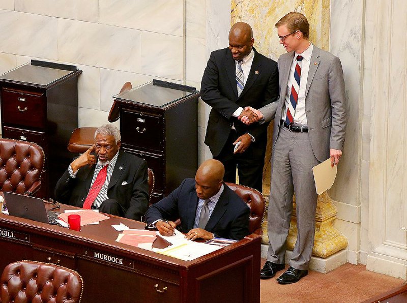 Rep. Fred Love (left) greets Rep. Grant Hodges during debate Thursday in the House on Hodges’ bill allowing teachers to opt out of labor unions or professional associations at any time. Love spoke against the bill, which passed 60-22. 