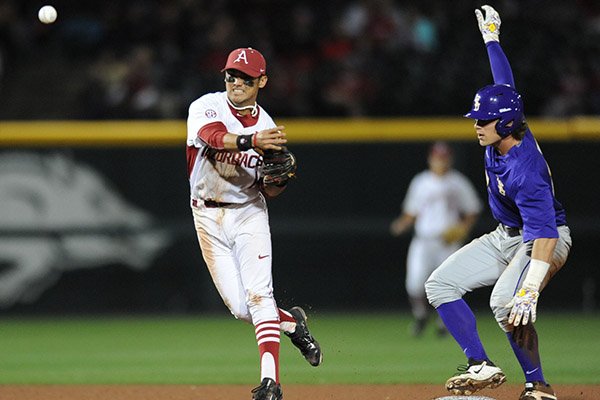 Second baseman Rick Nomura (right) of Arkansas makes the relay throw to first after forcing out Jared Foster of LSU to score a run during the fourth inning Friday, March 20, 2015, at Baum Stadium in Fayetteville.