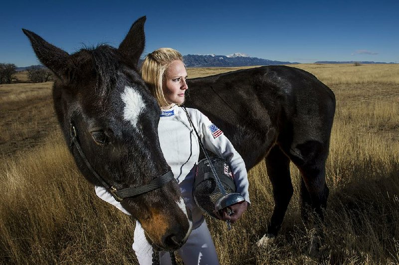 Margaux Isaksen, an Olympic modern pentathlete from Fayetteville, stands in her fencing gear with Gemma, the horse, Saturday, December 27, 2014. Isaksen has been training at the Olympic Training Center in Colorado Springs, Colo. for seven years. The modern pentathlon consists of events in fencing, equestrian, running, shooting and swimming. Isaksen trains eight hours a day, six days a week. 