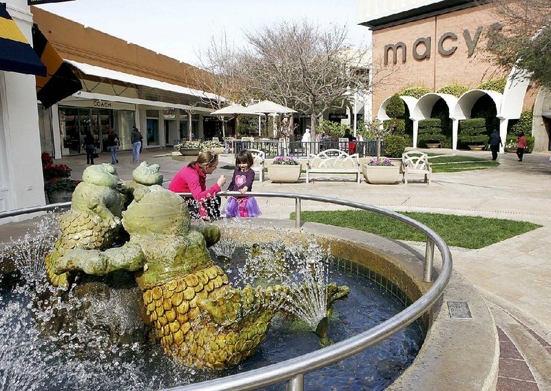 FILE - In this Feb. 16, 2010 file photo, a woman and a young girl stand at a fountain at the Stanford Shopping Center, a Simon Property Group property, in Palo Alto, Calif. Simon Property Group on Monday, March 9, 2015 said it is launching a hostile bid worth about $16 billion for Macerich Co., after saying the rival mall operator refused to discuss a combination. (AP Photo/Paul Sakuma, File)