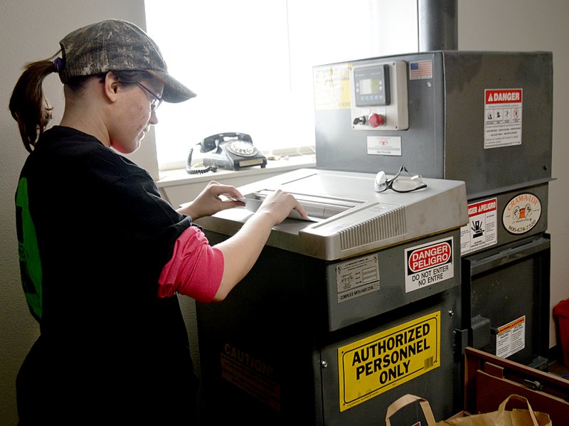 Janelle Jessen/Siloam Sunday Bobbie Sue Whitlock fed papers into the shredding machine. The machine can cross-shred up to 100 pounds of paper an hour and package the shreds into bales to be sent for recycling.