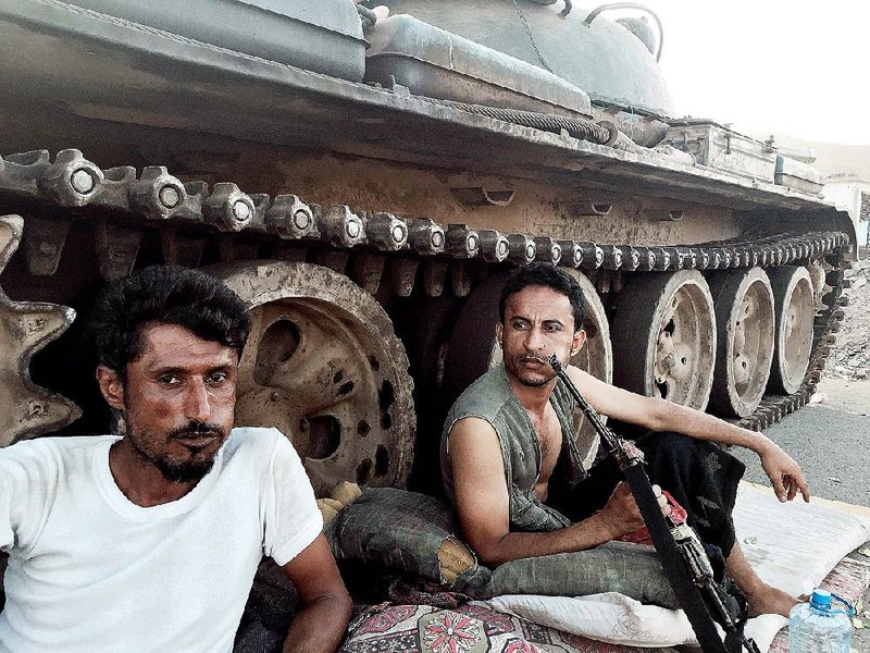 Members of a militia group loyal to Yemen's President Abed Rabbo Mansour Hadi, known as the Popular Committees, chew qat, Yemen's favorite drug, as they sit next to their tank, guarding a major intersection in Aden, Yemen, Saturday, March 21, 2015. Yemen's Shiite rebels issued a call to arms Saturday to battle forces loyal to the embattled President Hadi, as U.S. troops evacuated a southern air base over al-Qaida militants seizing a nearby city, authorities said. (AP Photo/Hamza Hendawi)