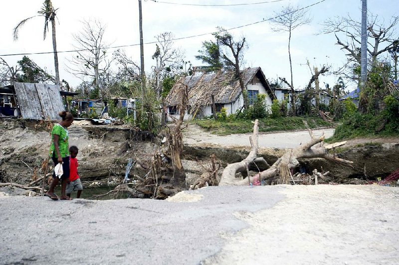 People walk past a washed-out bridge on the island of Efate, Vanuatu on Saturday, March 21, 2015. A week after Cyclone Pam tore through the South Pacific archipelago with winds of 270 kilometers (168 miles) per hour, people are focused on the task of rebuilding. (AP Photo/Nick Perry)