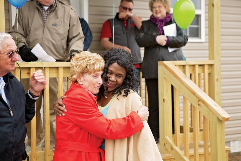 Patsy Fortner, left, hugs Shenel Sandidge, executive director of Habitat for Humanity of Faulkner County, at the dedication Thursday of homes in Mayflower for tornado victims. Fortner, who has been diagnosed with cancer, had her new home fully funded. Habitat for Humanity of Faulkner County holds the deeds to six of the other homes built in Mayflower. Five homes were scheduled to be dedicated Saturday in Vilonia. Also pictured is Jarrel Robertson, left, a friend of Fortner’s. Christian Aid Ministries provided the builders in Mayflower, and Apostolic Christian World Relief volunteers built the Vilonia homes. Other churches, relief organizations and businesses contributed to the effort.
