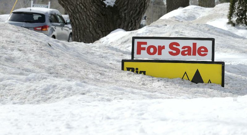 FILE - In this Feb. 24, 2015 file photo, a "For Sale" sign pokes out of about 4 feet of snow in the front yard of a home listed in Derry, N.H. The National Association of Realtors releases existing home sales for February on Monday, March 23, 2015. (AP Photo/Charles Krupa, File)