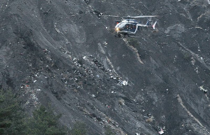 A rescue helicopter flies over scattered debris from a Germanwings jetliner with 150 people aboard that crashed Tuesday near Seyne-les-Alpes in the French Alps.