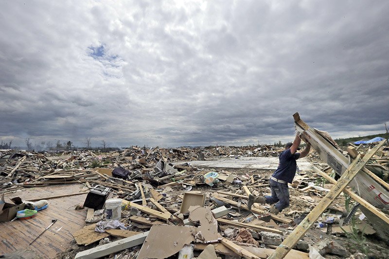 Dustin Shaw lifts debris as he searches through what is left of his sister's house at Parkwood Meadows neighborhood in Vilonia on April 20, 2014. 