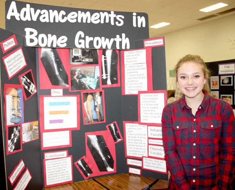 LYNN KUTTER ENTERPRISE-LEADER Madison Osnes, an eighth-grader at Lynch Middle School in Farmington, displays her science fair project during the school&#8217;s Math and Science Family Night. Osnes has undergone multiple surgeries on her left leg and her project was on how three of the procedures affected bone growth.