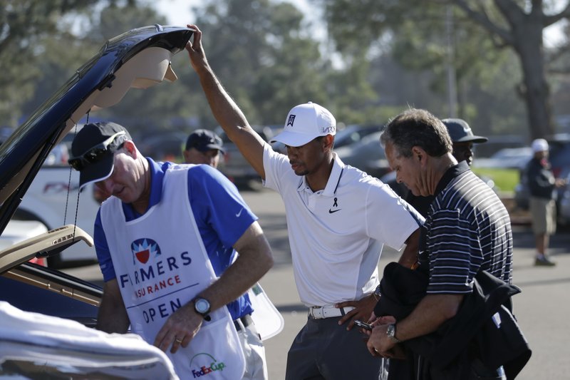 In this Feb. 5, 2015, file photo, Tiger Woods, center, loads his car after withdrawing during the first round of the Farmers Insurance Open golf tournament in San Diego. Woods was fleeing from a golf tournament in mid-round, mumbling something about improper activation of his glutes. Two weeks before the Masters he's still missing in action, though his fans have plenty of ideas on how to get his mojo back.