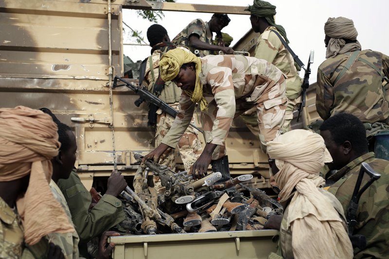 In this file photo taken on Wednesday March 18, 2015, Chadian soldiers collect weapons seized from Boko Haram fighters  in the Nigerian city of Damasak, Nigeria.  Hundreds of civilians, including many children, have been kidnapped and are being used as human shields by Boko Haram extremists, a top Nigerian official confirmed Wednesday, March 25, 2015. 