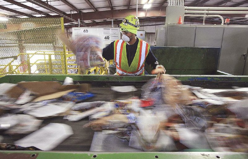Ontario Jones sorts paper and other recyclable materials Thursday morning at Waste Management Inc.’s recycling facility in Little Rock.The Regional Recycling and Waste Reduction District board approved a $150,000 contract for a recycling-incentives program in Pulaski County. 