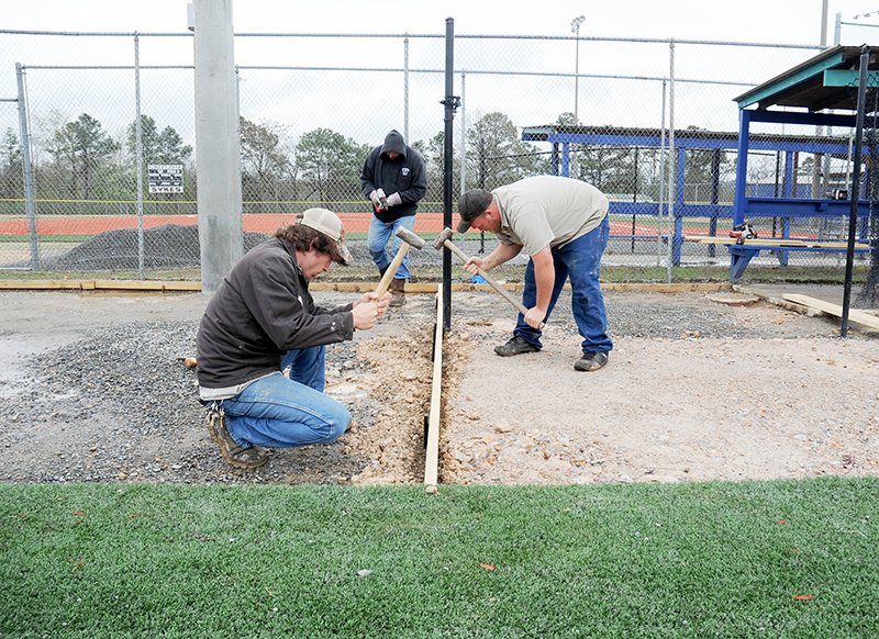 The Sentinel-Record/Mara Kuhn FIELD PREP: Hot Springs Parks and Trails employees Martin Graf, left, Jonathan Patman, right, and John Elmore install framing on Field 1 at Kimery Park on Thursday in preparation for the addition of the new Pour In Place surface.