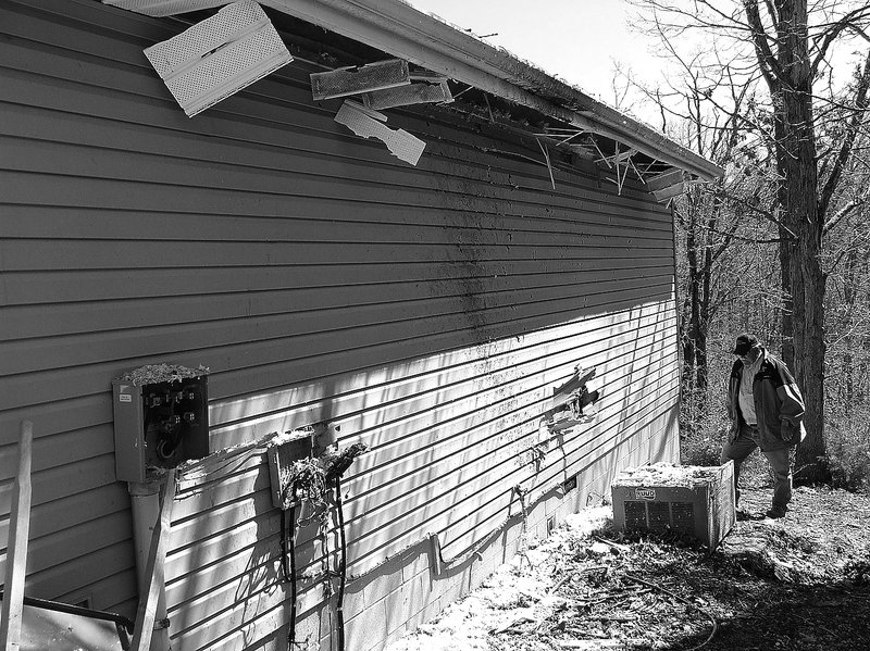 NWA Democrat-Gazette/TOM A. THRONE Steve Cash, a Bella Vista building inspecto, looks over the damage Thursday on the side of the house at 29 Lord Nelson Drive caused by a lightning strike Wednesday evening. It was one of 22 reported strikes handled by the Bella Vista Fire Department between late Wednesday evening and early Thursday morning.