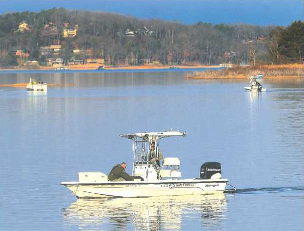 Personnel in an Arkansas Game & Fish Commission boat (center) and officials from other agencies search Beaver Lake on Wednesday for a missing woman near the Larue community east of Rogers.
