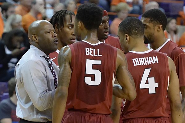 Arkansas head coach Mike Anderson, left, talks to his players during the second half of an NCAA college basketball game against Clemson, Sunday, Dec. 7, 2014, in Clemson, S.C. Clemson won 68-65. (AP Photo/Richard Shiro)