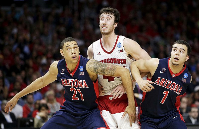Arizona’s Brandon Ashley (21) and Gabe York (1) try to block out Wisconsin forward Frank Kaminsky after a free throw during the second half of Saturday’s West Region final at the Staples Center in Los Angeles. The Wildcats’ defense didn’t have much luck containing Kaminsky, who led the Badgers with 29 points and six rebounds. 